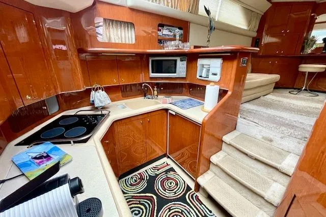 Slide: The Image of Luxurious 2001 Sea Ray 420 Aft Cabin interior with modern kitchen and elegant wood finishes. - 30