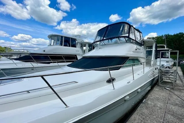 Slide: The Image of 2001 Sea Ray 420 Aft Cabin yacht docked under a blue sky with clouds. - 6