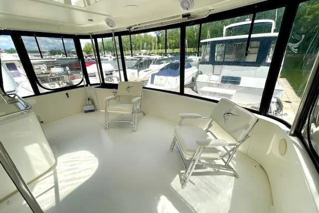Slide: The Image of 2001 Sea Ray 420 Aft Cabin interior with chairs, large windows, and marina view. - 8