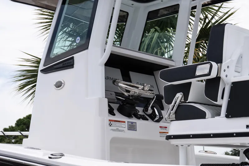 Slide: The Image of 2026 Blackfin 262 HB boat helm with modern controls and seating, surrounded by palm trees. - 11