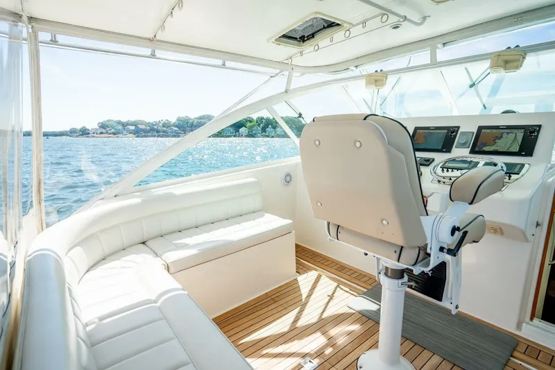 Slide: The Image of 2004 Cabo 40 Express yacht interior with helm, seating, and navigation screens on a sunny day. - 30