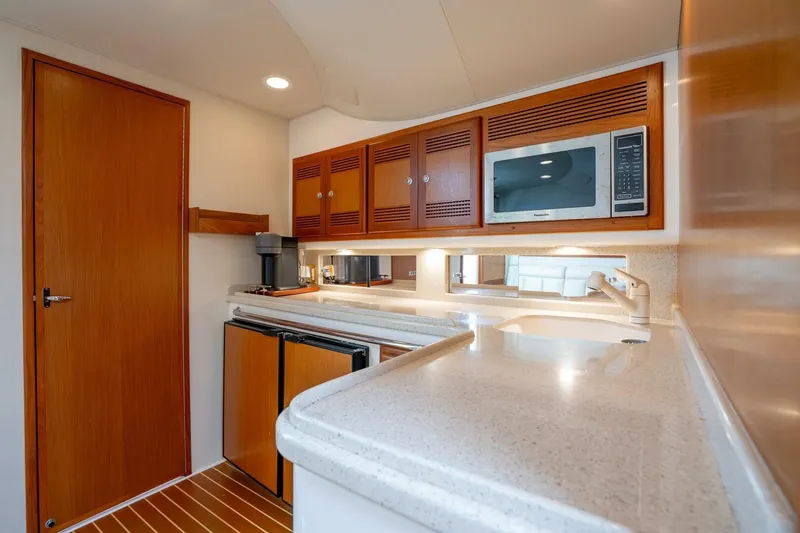 Slide: The Image of 2004 Cabo 40 Express yacht kitchen with wood cabinets, microwave, and modern appliances. - 8