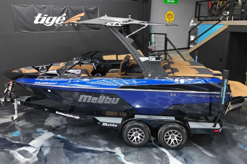 Slide: The Image of 2021 Malibu Wakesetter 20 VTX boat in showroom, blue and black design, on trailer. - 6