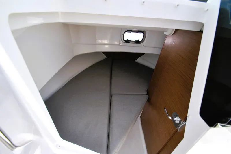 Slide: The Image of 2019 Jeanneau NC 795 Sport cabin interior with cushioned sleeping area and small window. - 15