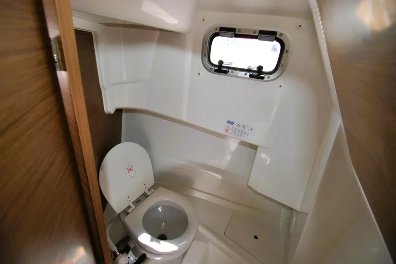 Slide: The Image of 2019 Jeanneau NC 795 Sport boat bathroom with toilet and porthole window. - 16