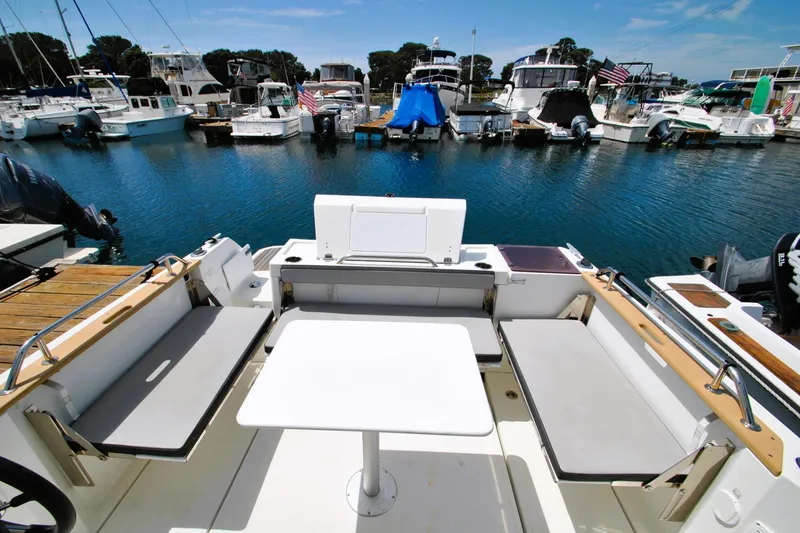 Slide: The Image of 2019 Jeanneau NC 795 Sport boat interior with seating and table, docked at marina. - 28