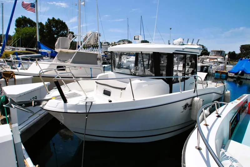 Slide: The Image of 2019 Jeanneau NC 795 Sport boat docked in a marina under clear blue skies. - 3