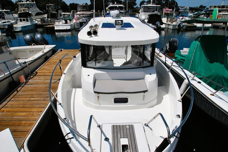 Slide: The Image of 2019 Jeanneau NC 795 Sport boat docked at a marina, surrounded by other vessels. - 4