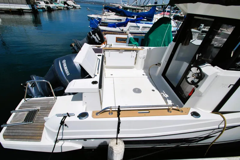 Slide: The Image of 2019 Jeanneau NC 795 Sport boat docked, featuring spacious deck and Yamaha outboard motor. - 6