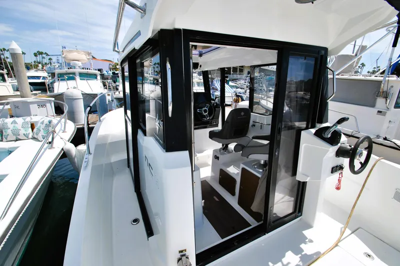 Slide: The Image of 2019 Jeanneau NC 795 Sport boat interior, featuring helm and seating, docked at marina. - 9