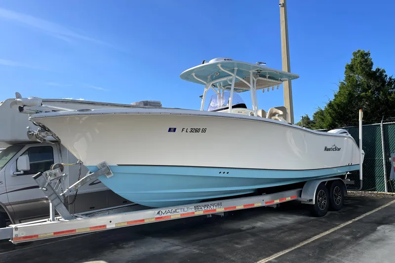 The Image of 2020 NauticStar 28 XS boat on trailer, white and blue, parked outdoors. - 0