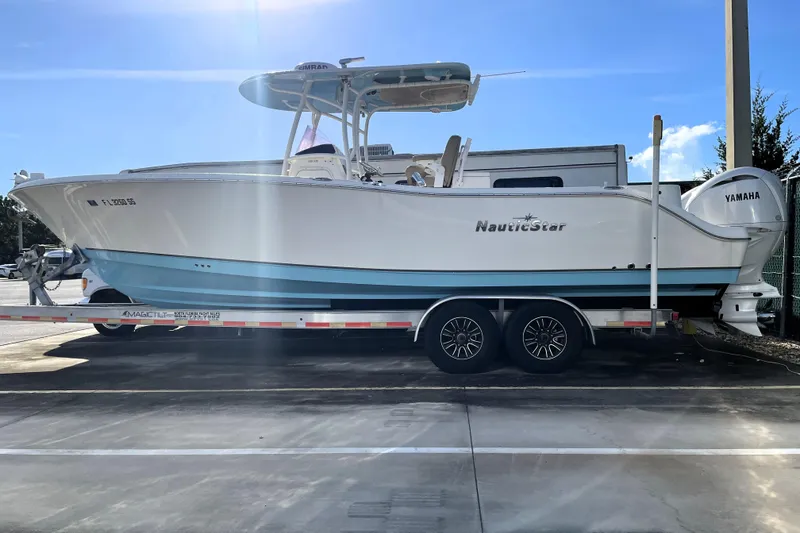 Slide: The Image of 2020 NauticStar 28 XS boat on trailer, featuring Yamaha engine, parked outdoors. - 2