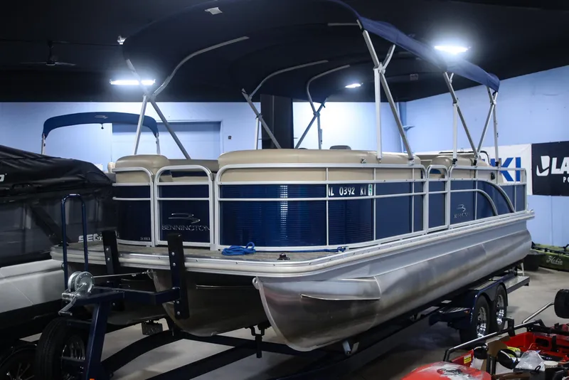 Slide: The Image of 2015 Bennington 24 SSLX pontoon boat with blue canopy in indoor showroom. - 0