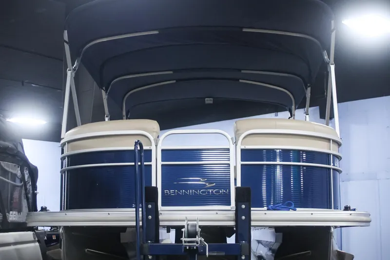 Slide: The Image of 2015 Bennington 24 SSLX pontoon boat with blue and beige design, under indoor lighting. - 1