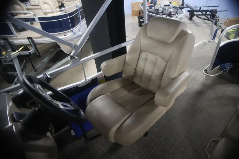 Slide: The Image of Captain's chair in 2015 Bennington 24 SSLX pontoon boat, featuring beige upholstery and steering wheel. - 11