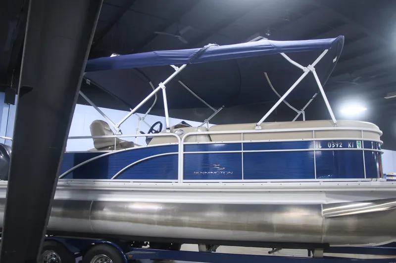 Slide: The Image of 2015 Bennington 24 SSLX pontoon boat with blue canopy in indoor showroom. - 4