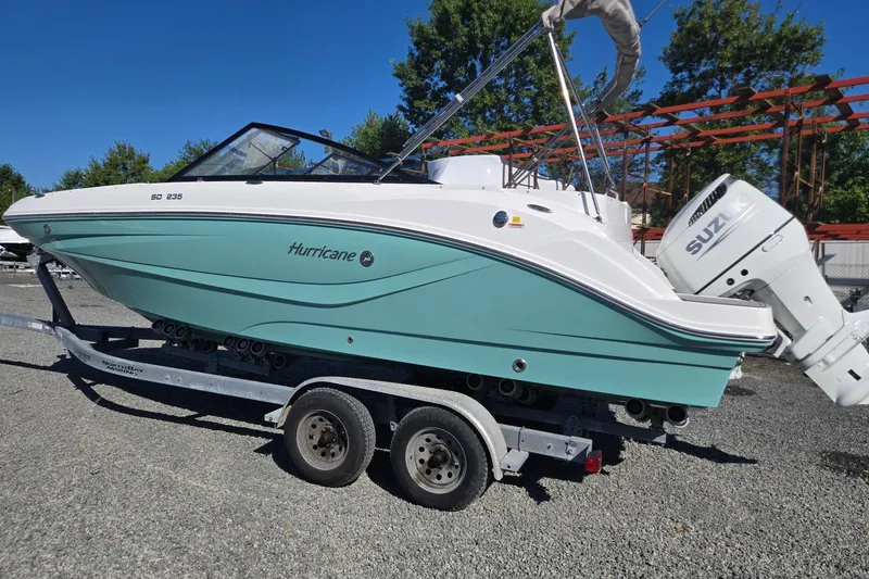 Slide: The Image of 2026 Hurricane SunDeck 235 OB boat on trailer, featuring Suzuki outboard motor. - 2