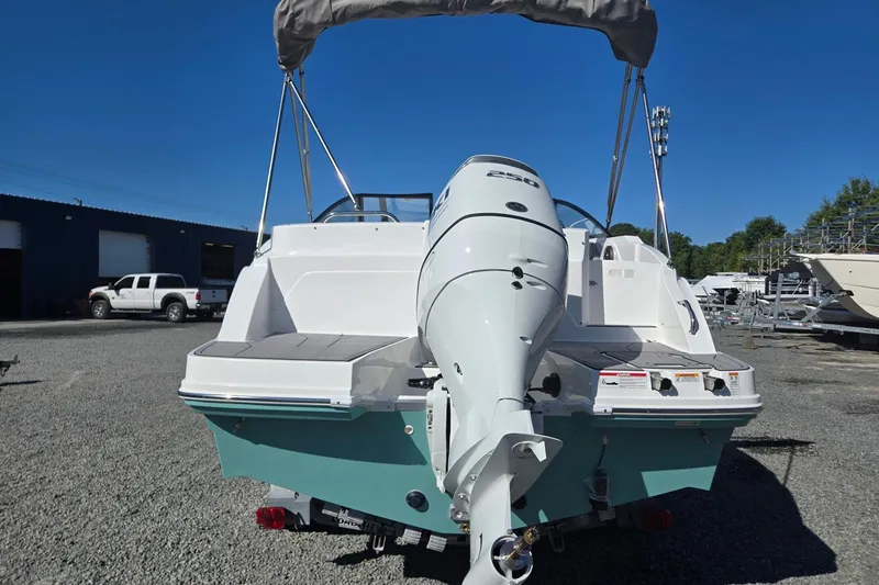 Slide: The Image of 2026 Hurricane SunDeck 235 OB boat with outboard motor, parked on gravel lot. - 4