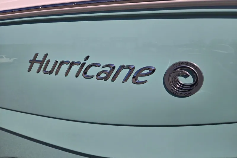 Slide: The Image of 2026 Hurricane SunDeck 235 OB boat logo, Coastal Edition emblem on light blue surface. - 46