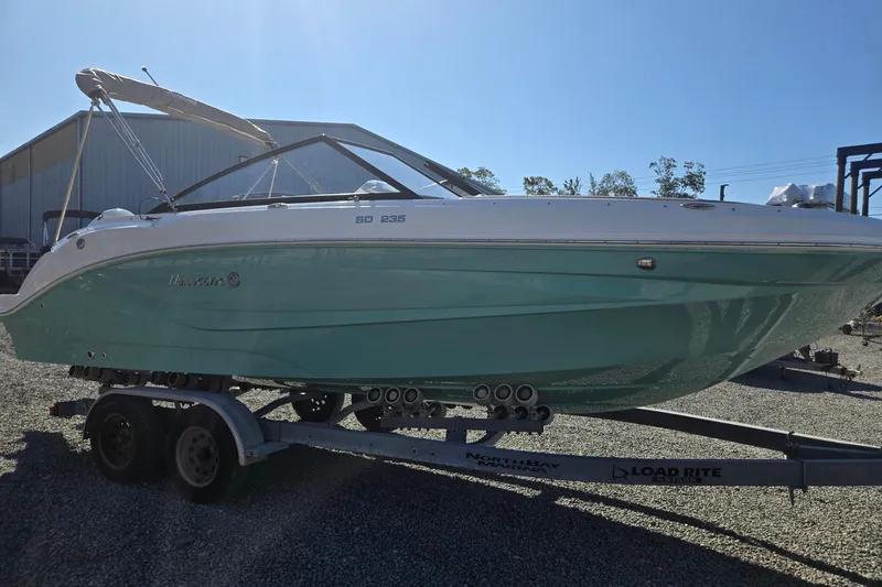 Slide: The Image of 2026 Hurricane SunDeck 235 OB boat on trailer, light blue hull, outdoor setting. - 7