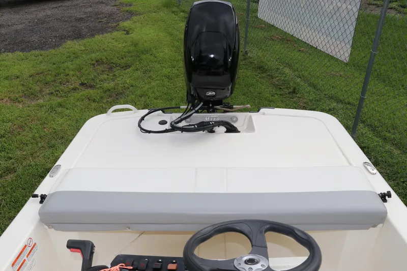 Slide: The Image of 2023 Mako Pro Skiff 13 CC boat with outboard motor, parked on grass. - 10