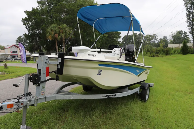 Slide: The Image of 2023 Mako Pro Skiff 13 CC boat with blue canopy on trailer, parked on grass. - 3