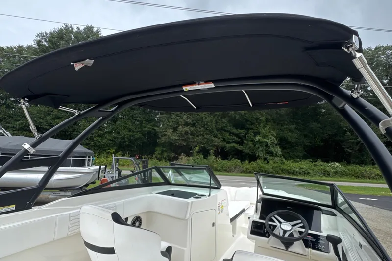Slide: The Image of 2023 Searay SPX 210 IO boat interior with black canopy and steering console. - 23