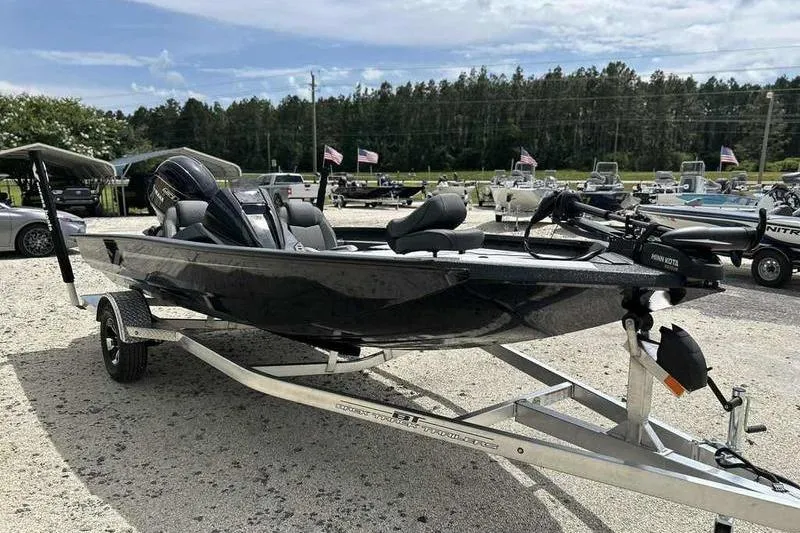 Slide: The Image of 2026 Xpress H18 Bay boat on trailer, parked outdoors with trees and flags in background. - 2