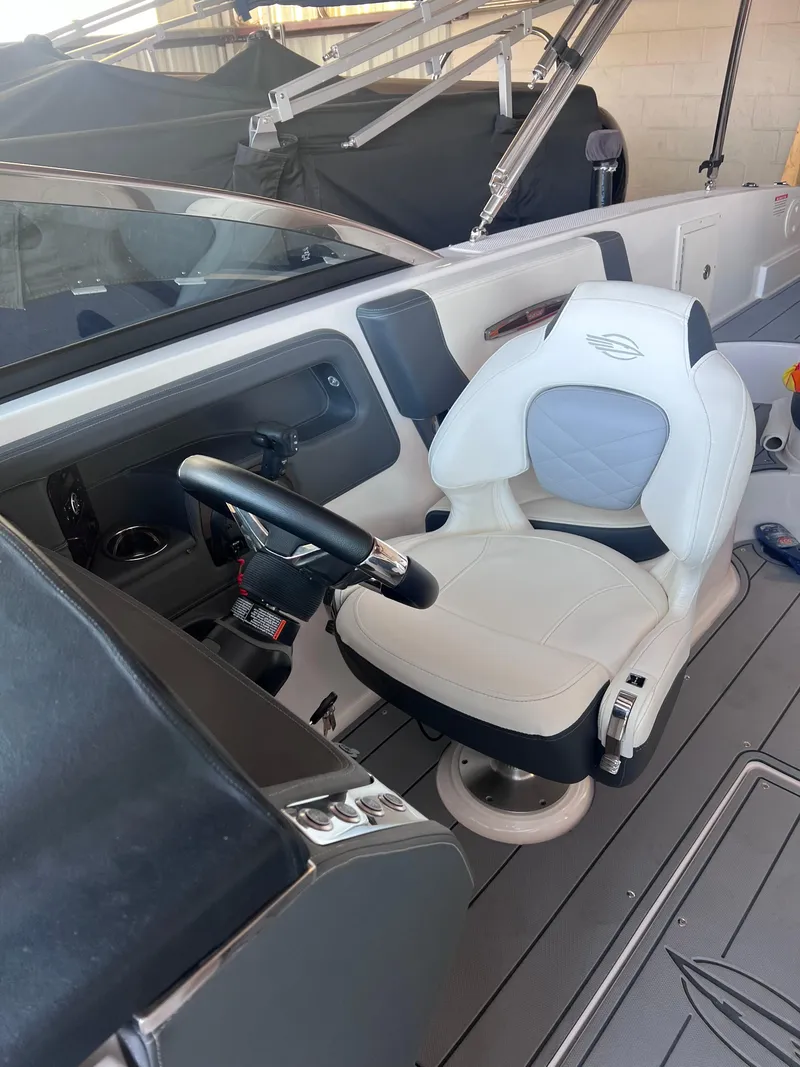 Slide: The Image of 2022 Chaparral 267 SSX boat interior with white captain's chair and steering wheel. - 22