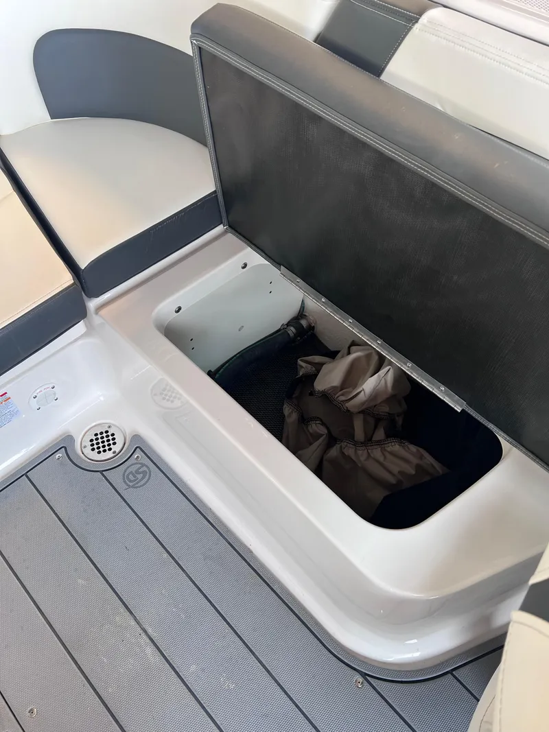 Slide: The Image of Storage compartment in 2022 Chaparral 267 SSX boat with open seat revealing life jackets. - 34