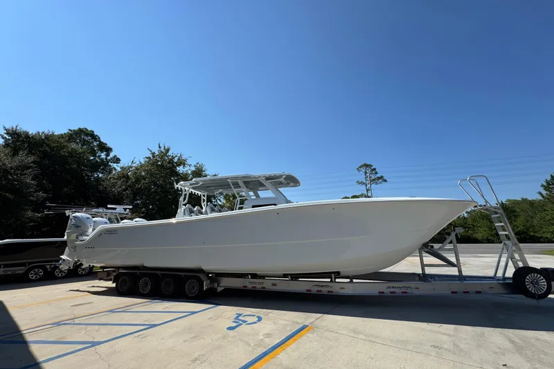 Slide: The Image of 2026 Invincible 46 Catamaran on trailer, parked outdoors under clear blue sky. - 10
