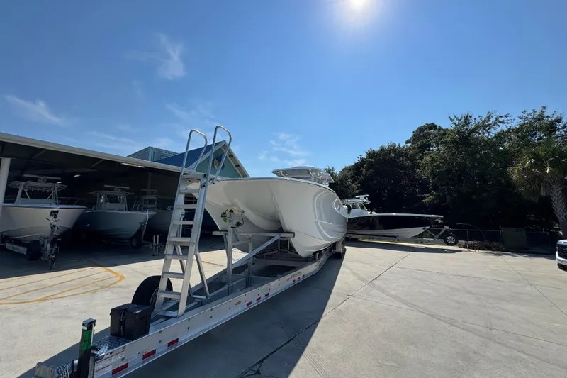 Slide: The Image of 2026 Invincible 46 Catamaran on trailer under sunny sky, surrounded by trees and other boats. - 6