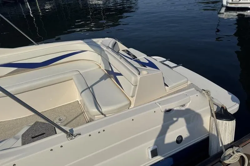 Slide: The Image of 2007 Rinker 282 boat docked, featuring white and blue seating, with water reflections. - 17