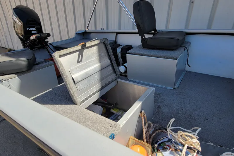 Slide: The Image of 2010 Tracker Guide V 15 Laker boat interior with storage compartment and motor. - 13