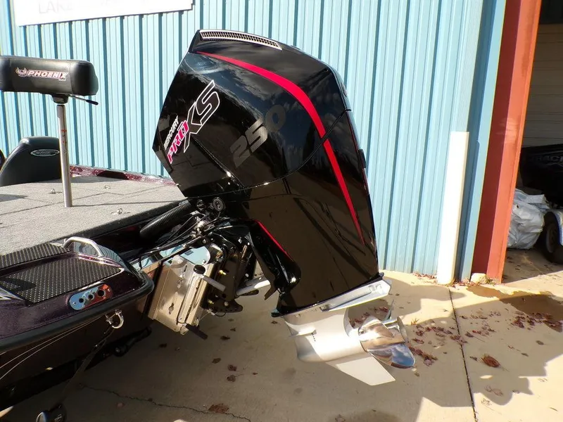 Slide: The Image of 2025 Phoenix 721 ZXL boat with powerful outboard motor, parked near blue metal building. - 5