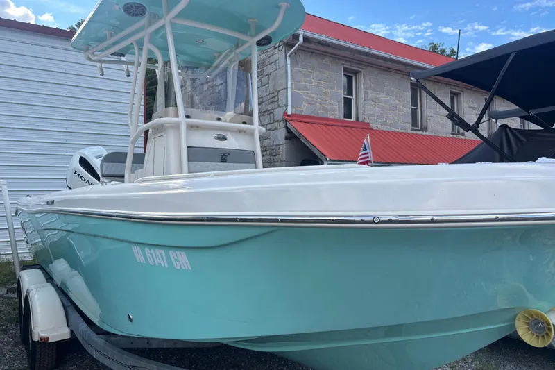 The Image of 2025 Carolina Skiff 23 Ultra Elite boat on trailer, light blue hull, parked near building. - 0