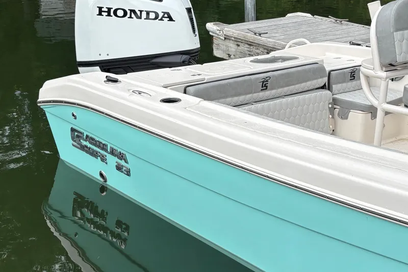 Slide: The Image of 2025 Carolina Skiff 23 Ultra Elite boat with Honda engine, docked on calm water. - 14
