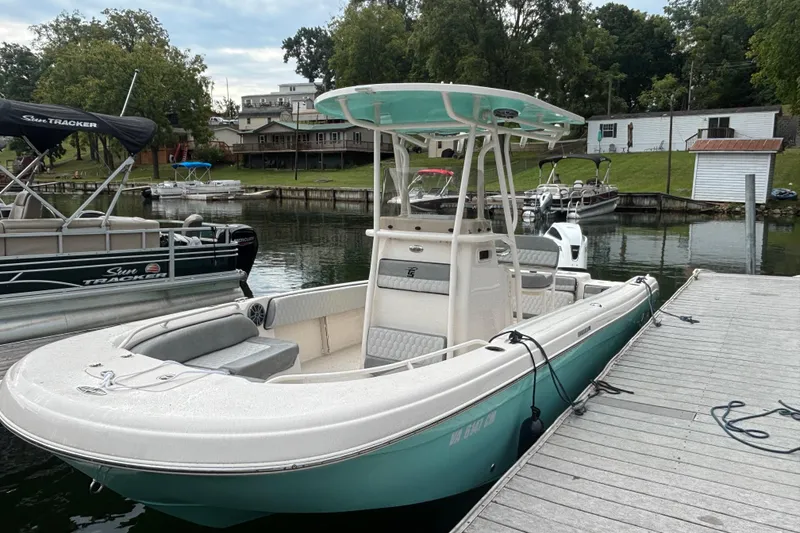 Slide: The Image of 2025 Carolina Skiff 23 Ultra Elite boat docked at a marina, surrounded by other boats. - 15