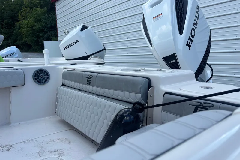 Slide: The Image of 2025 Carolina Skiff 23 Ultra Elite boat with Honda outboard engines, docked near a metal building. - 6