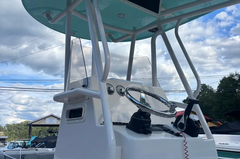 Slide: The Image of 2025 Carolina Skiff 23 Ultra Elite boat console with steering wheel and gauges under blue sky. - 7