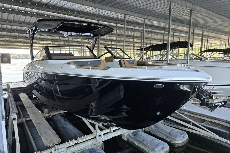 Slide: The Image of 2026 Cobalt R31 boat in marina, sleek black design under covered dock. - 0