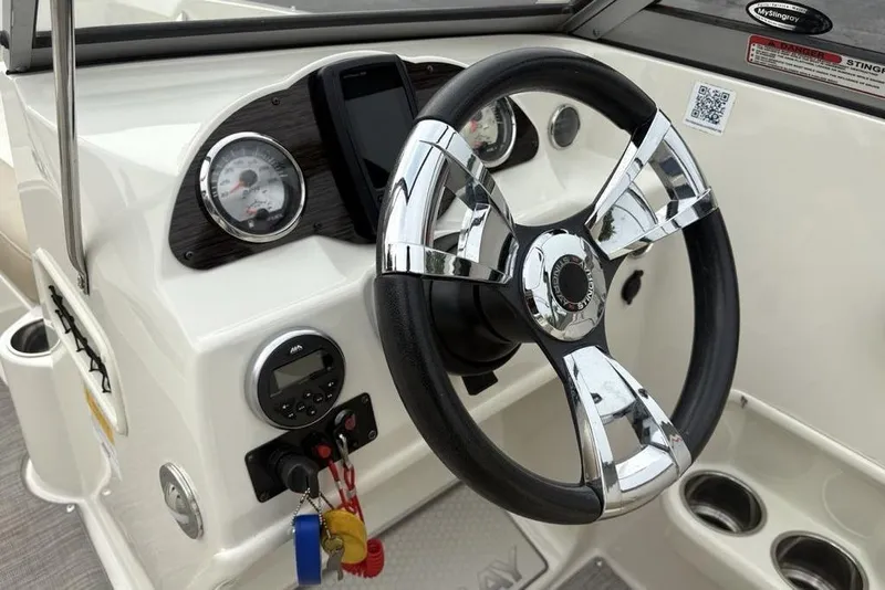 Slide: The Image of Steering wheel and dashboard of 2017 Stingray 191DC O/B boat, featuring chrome accents. - 17