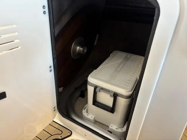 Slide: The Image of Stingray 211DC 2026 boat storage compartment with a white cooler inside. - 13