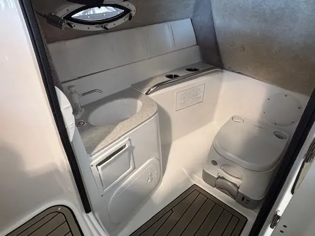 Slide: The Image of 2026 Stingray 211DC boat interior with compact bathroom, featuring sink and toilet. - 15