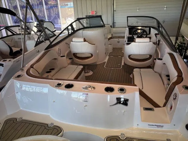 Slide: The Image of 2026 Stingray 211DC boat interior with white seating and wood accents in showroom. - 6