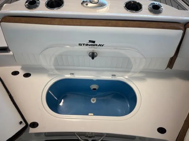 Slide: The Image of 2026 Stingray 211DC boat livewell with blue interior and cup holders. - 8