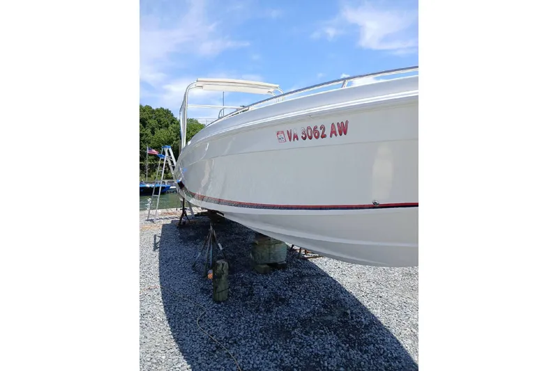 Slide: The Image of 1999 Wellcraft Scarab 302 Sport boat docked near residential area, covered and elevated. - 2