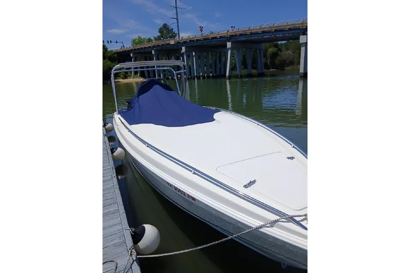 Slide: The Image of 1999 Wellcraft 302 Scarab Sport boat docked near a bridge, covered with a blue tarp. - 21