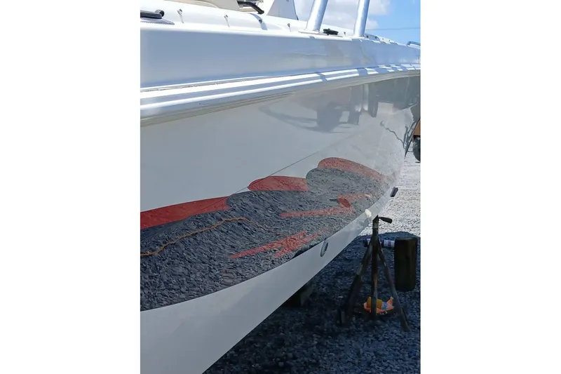 Slide: The Image of 1999 Wellcraft 302 Scarab Sport boat hull with reflective surface on gravel. - 25