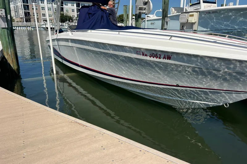 Slide: The Image of 1999 Wellcraft 302 Scarab Sport boat docked at marina, reflecting sunlight on water. - 79